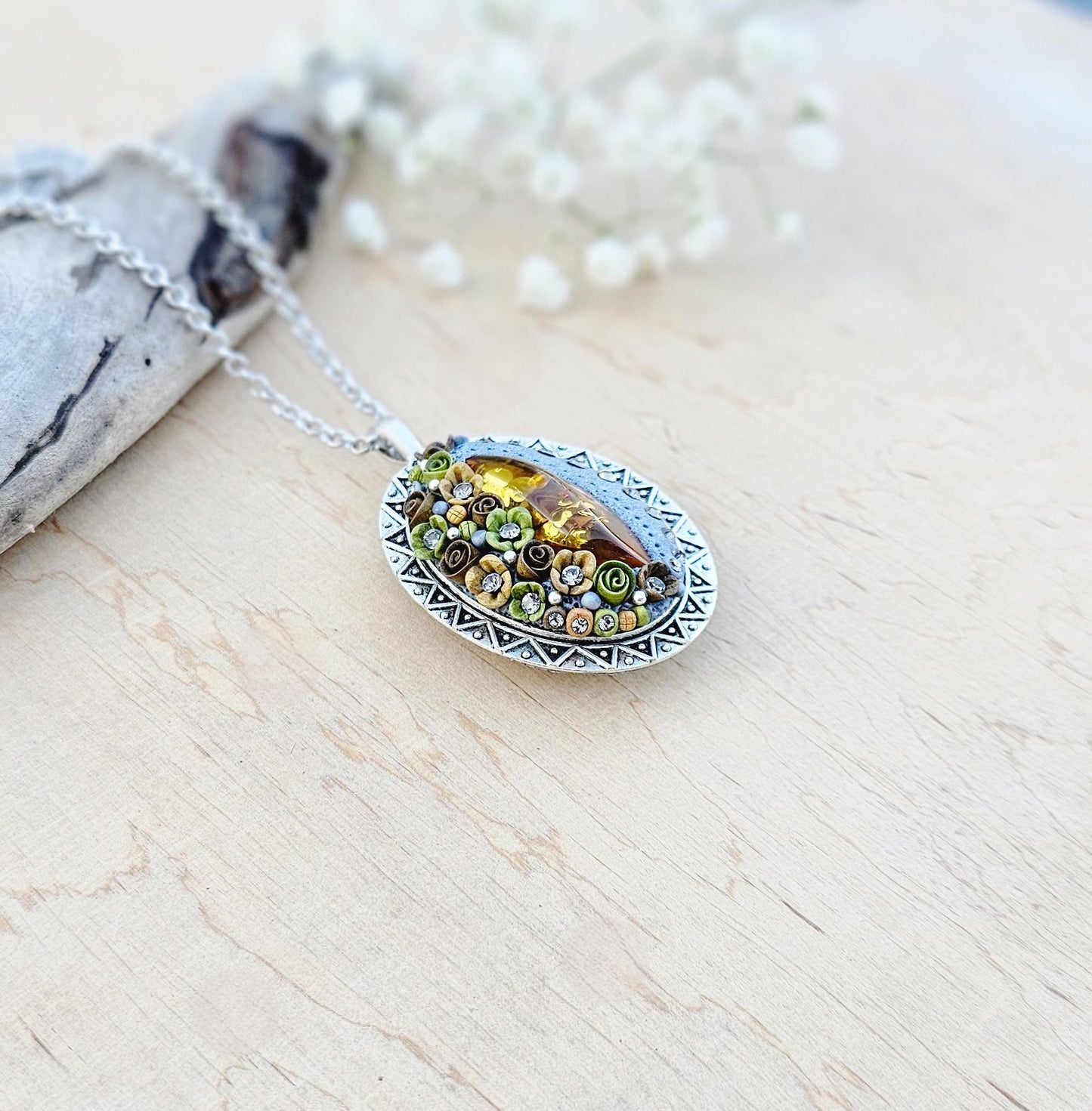 Pendant locket with amber, handmade flowers from polymer clay. On the other side, there is a locket with a heart that opens, inside which you can put a photo or a scent. A great gift for a loved one, or for yourself as a protective amulet.