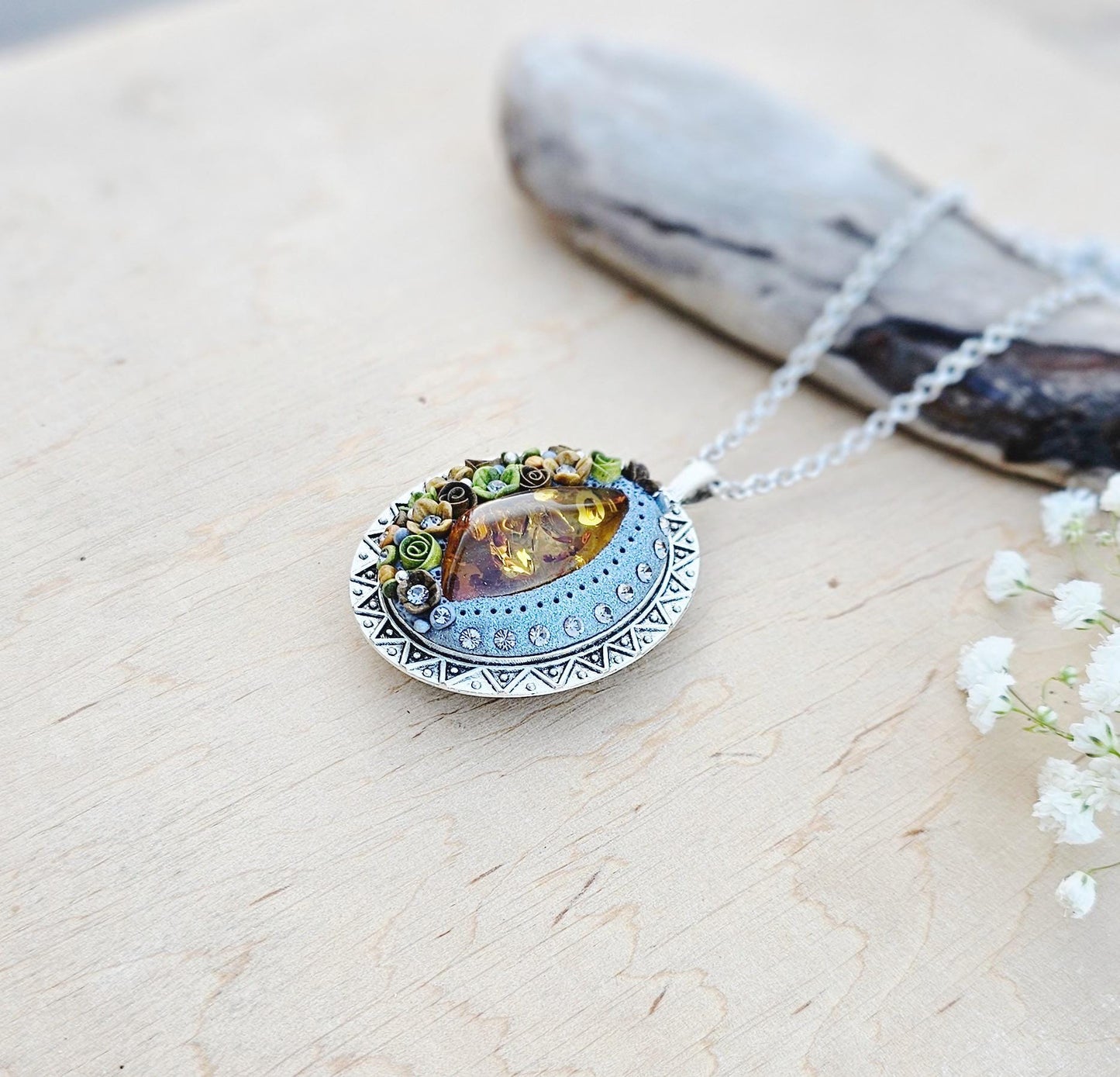 Pendant locket with amber, handmade flowers from polymer clay. On the other side, there is a locket with a heart that opens, inside which you can put a photo or a scent. A great gift for a loved one, or for yourself as a protective amulet.