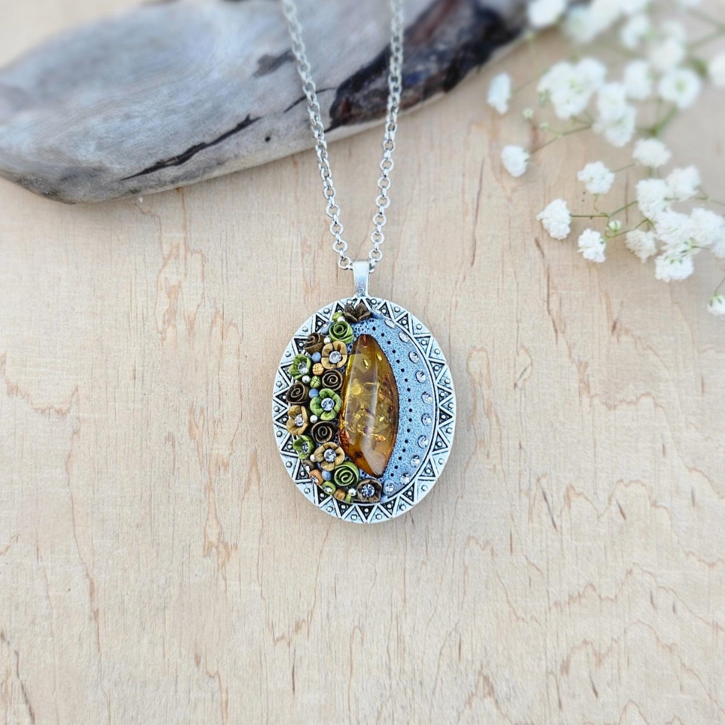 Pendant locket with amber, handmade flowers from polymer clay. On the other side, there is a locket with a heart that opens, inside which you can put a photo or a scent. A great gift for a loved one, or for yourself as a protective amulet.