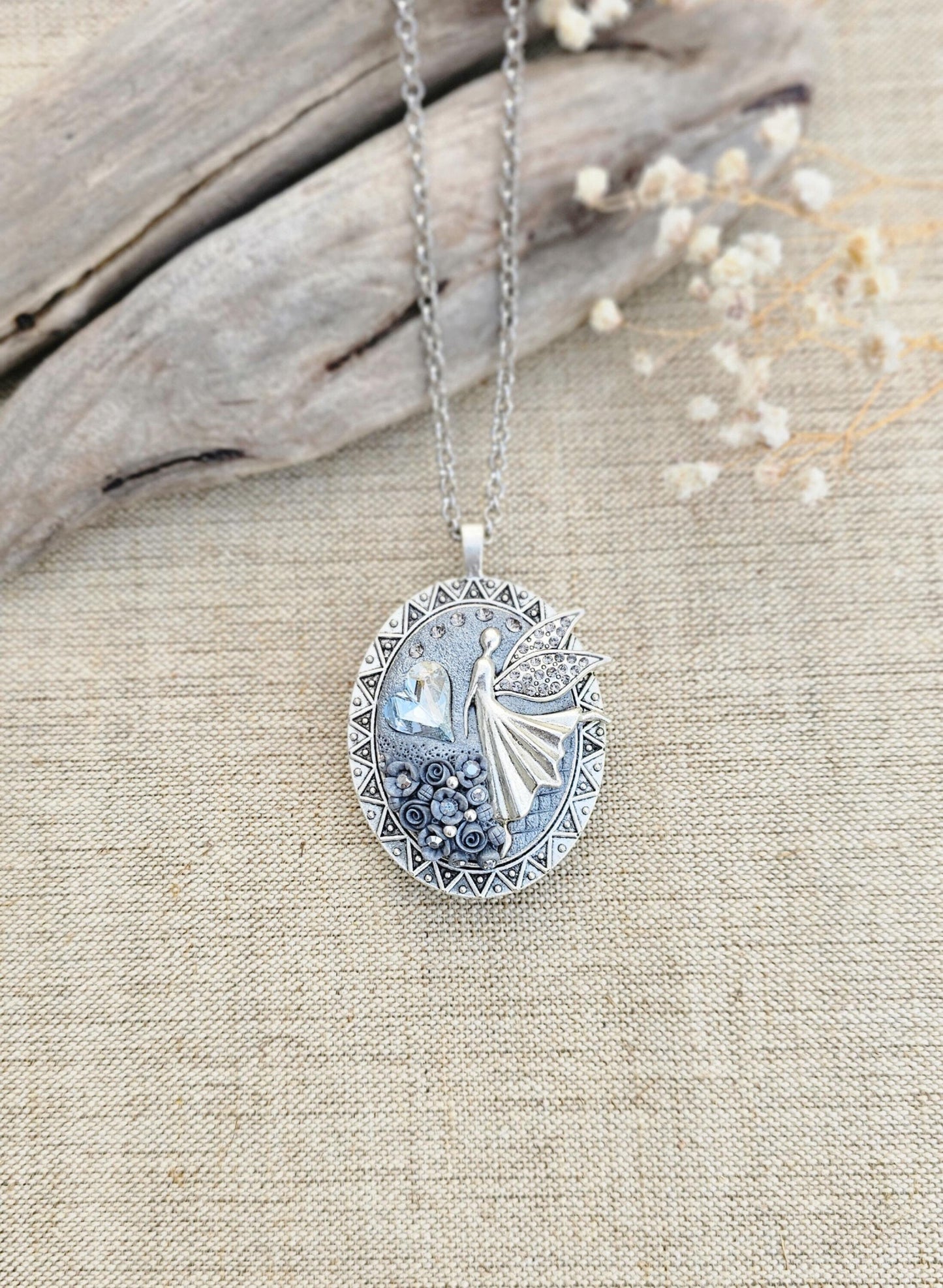 silver fairy pendant, gray floral locket, mystical jewelry, elegant necklace, fairy charm, crystal pendant, handcrafted accessory, unique fairy necklace, silver chain pendant, keepsake locket, photo locket, sophisticated charm, magical jewelry