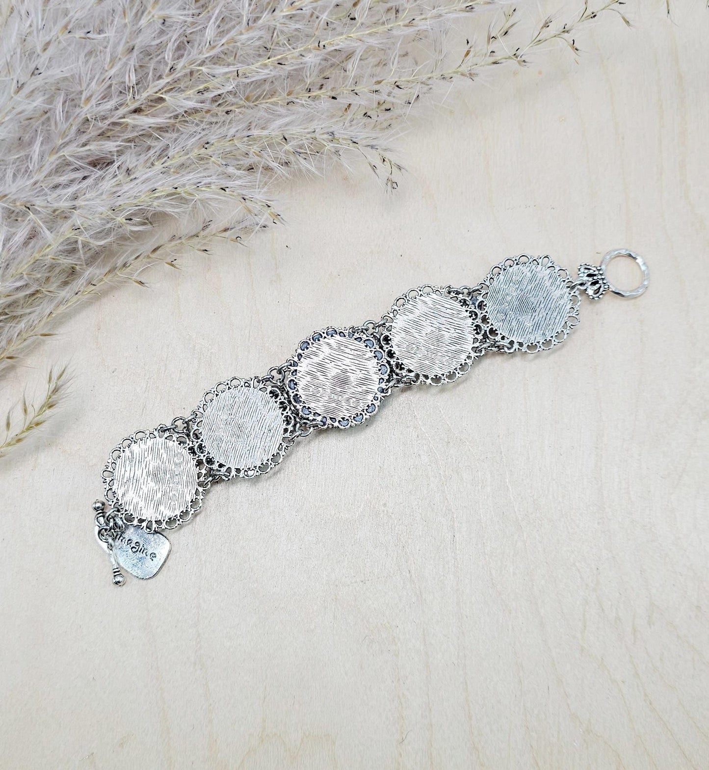 Amber-tone wide bracelet with sparkling crystals and intricate details. Features handmade polymer clay flowers, a functional locket with a red heart inside, and a detachable "imagine" charm.