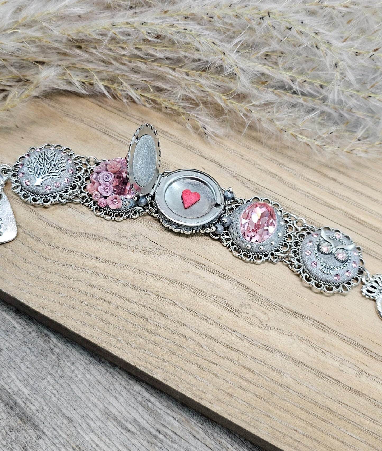 A handmade wide bracelet with pink crystals, polymer clay flowers, a Tree of Life charm, and an owl charm. Features a locket centerpiece with a hidden heart and a removable "Imagine" tag. Elegant and symbolic, perfect as a meaningful gift.