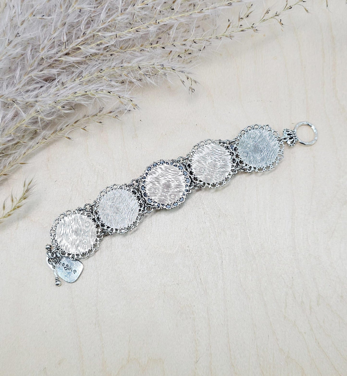A handmade wide bracelet with pink crystals, polymer clay flowers, a Tree of Life charm, and an owl charm. Features a locket centerpiece with a hidden heart and a removable "Imagine" tag. Elegant and symbolic, perfect as a meaningful gift.