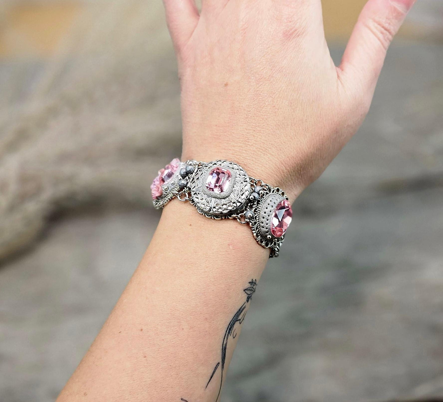 A handmade wide bracelet with pink crystals, polymer clay flowers, a Tree of Life charm, and an owl charm. Features a locket centerpiece with a hidden heart and a removable "Imagine" tag. Elegant and symbolic, perfect as a meaningful gift.