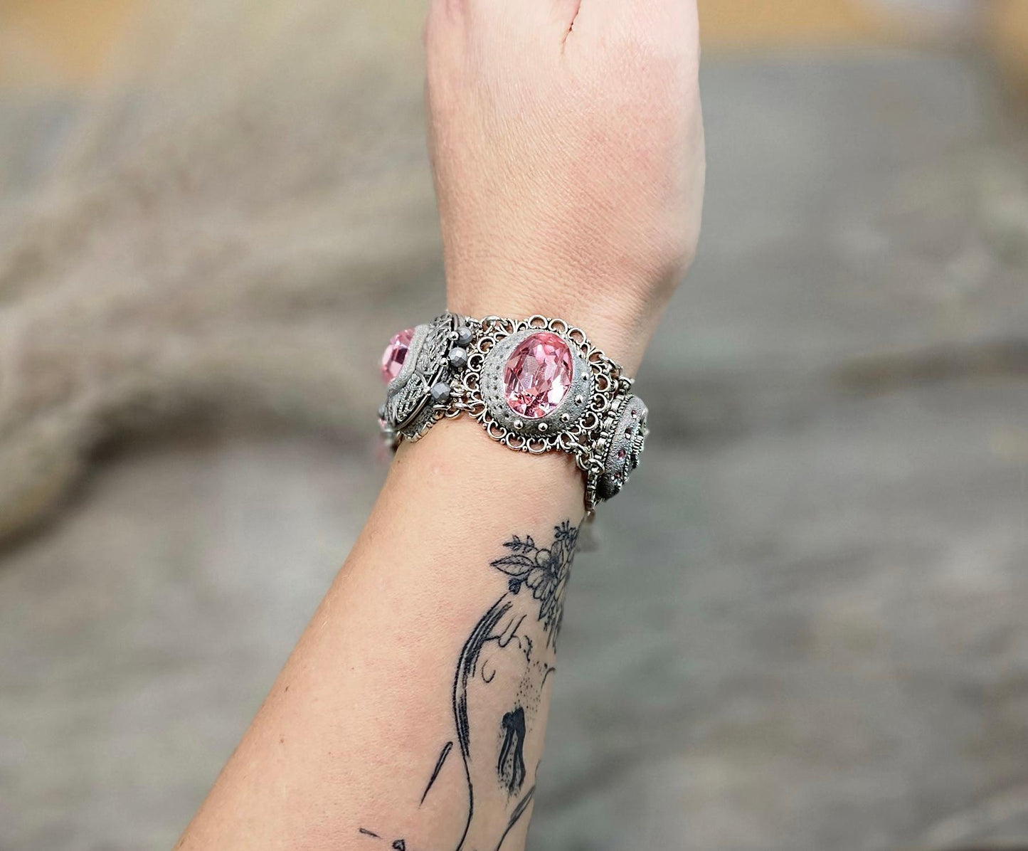 A handmade wide bracelet with pink crystals, polymer clay flowers, a Tree of Life charm, and an owl charm. Features a locket centerpiece with a hidden heart and a removable "Imagine" tag. Elegant and symbolic, perfect as a meaningful gift.