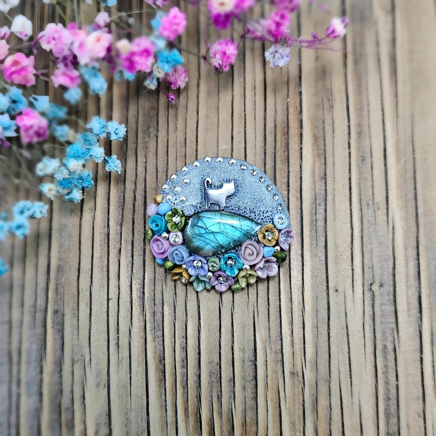 1️⃣ Front view: A handcrafted labradorite brooch featuring a silver-tone cat charm, surrounded by delicate polymer clay flowers in pastel colors. The shimmering gemstone displays a magical glow depending on the lighting.
2️⃣ Back view: The backside of the handmade cat brooch, featuring a secure screw-back pin for comfortable wear. A small red heart detail and subtle embellishments add an extra touch of uniqueness.
Let me know if you need any tweaks! 😊