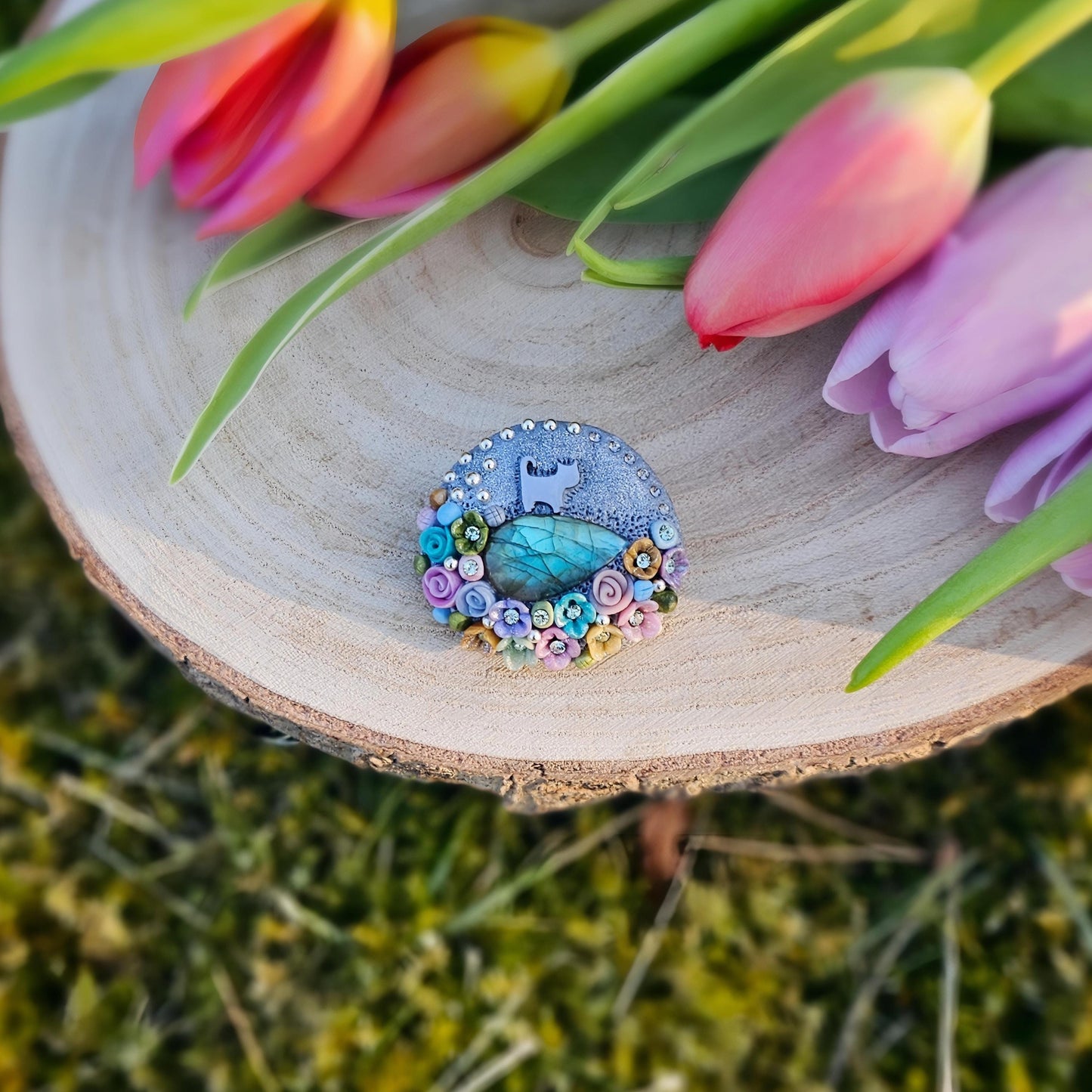 1️⃣ Front view: A handcrafted labradorite brooch featuring a silver-tone cat charm, surrounded by delicate polymer clay flowers in pastel colors. The shimmering gemstone displays a magical glow depending on the lighting.
2️⃣ Back view: The backside of the handmade cat brooch, featuring a secure screw-back pin for comfortable wear. A small red heart detail and subtle embellishments add an extra touch of uniqueness.
Let me know if you need any tweaks! 😊