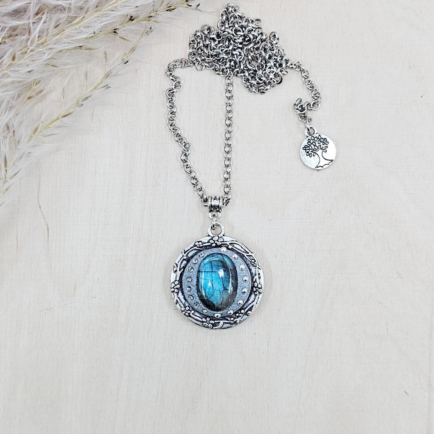 Silver vintage-style pendant necklace featuring a mesmerizing blue flash labradorite stone, set in an ornate medallion frame with intricate details.
