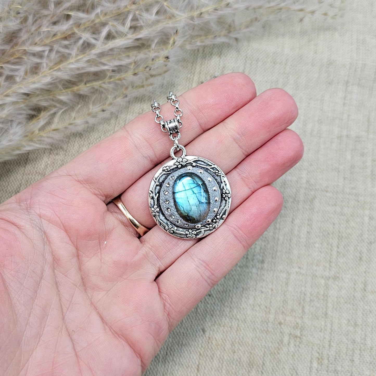 Silver vintage-style pendant necklace featuring a mesmerizing blue flash labradorite stone, set in an ornate medallion frame with intricate details.