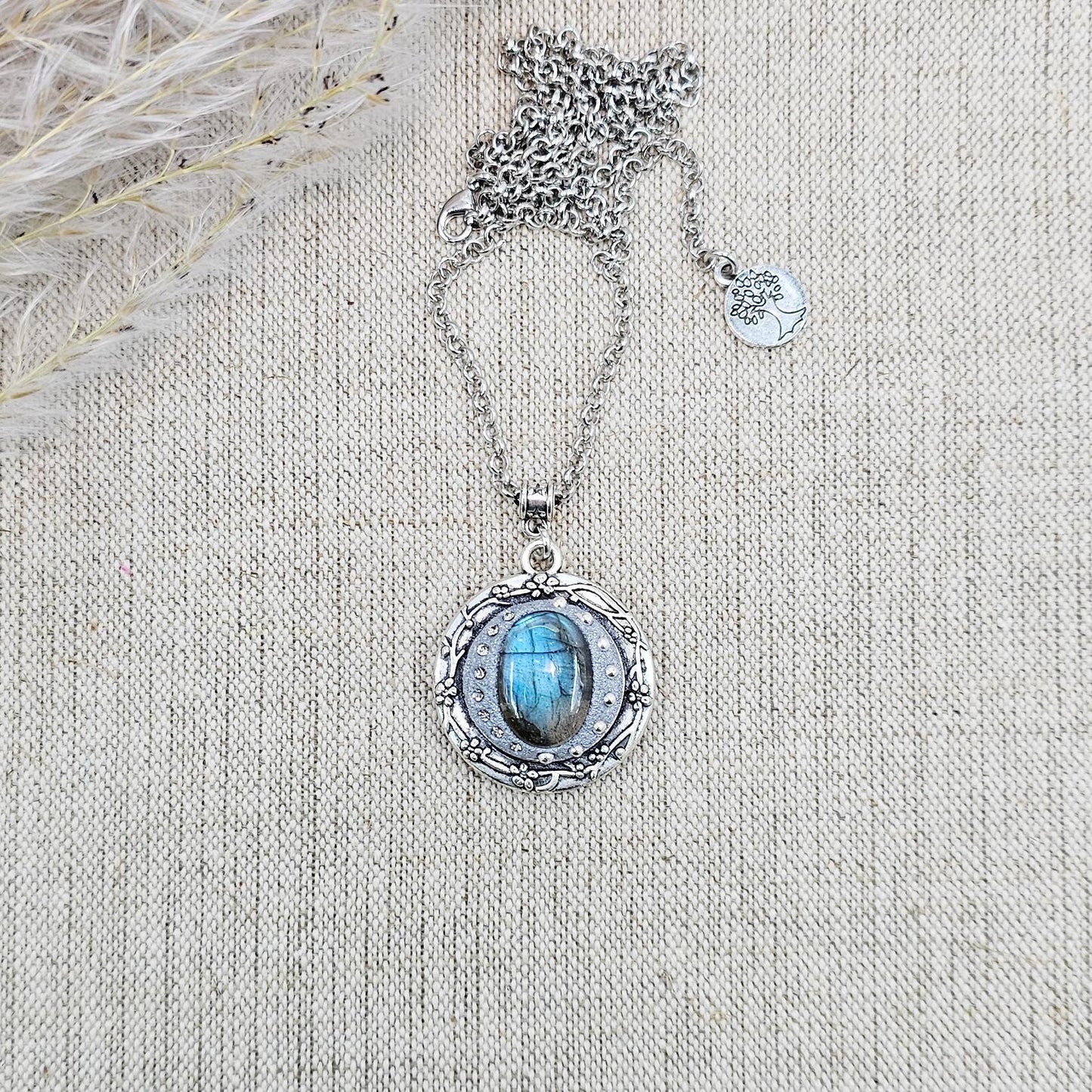 Silver vintage-style pendant necklace featuring a mesmerizing blue flash labradorite stone, set in an ornate medallion frame with intricate details.