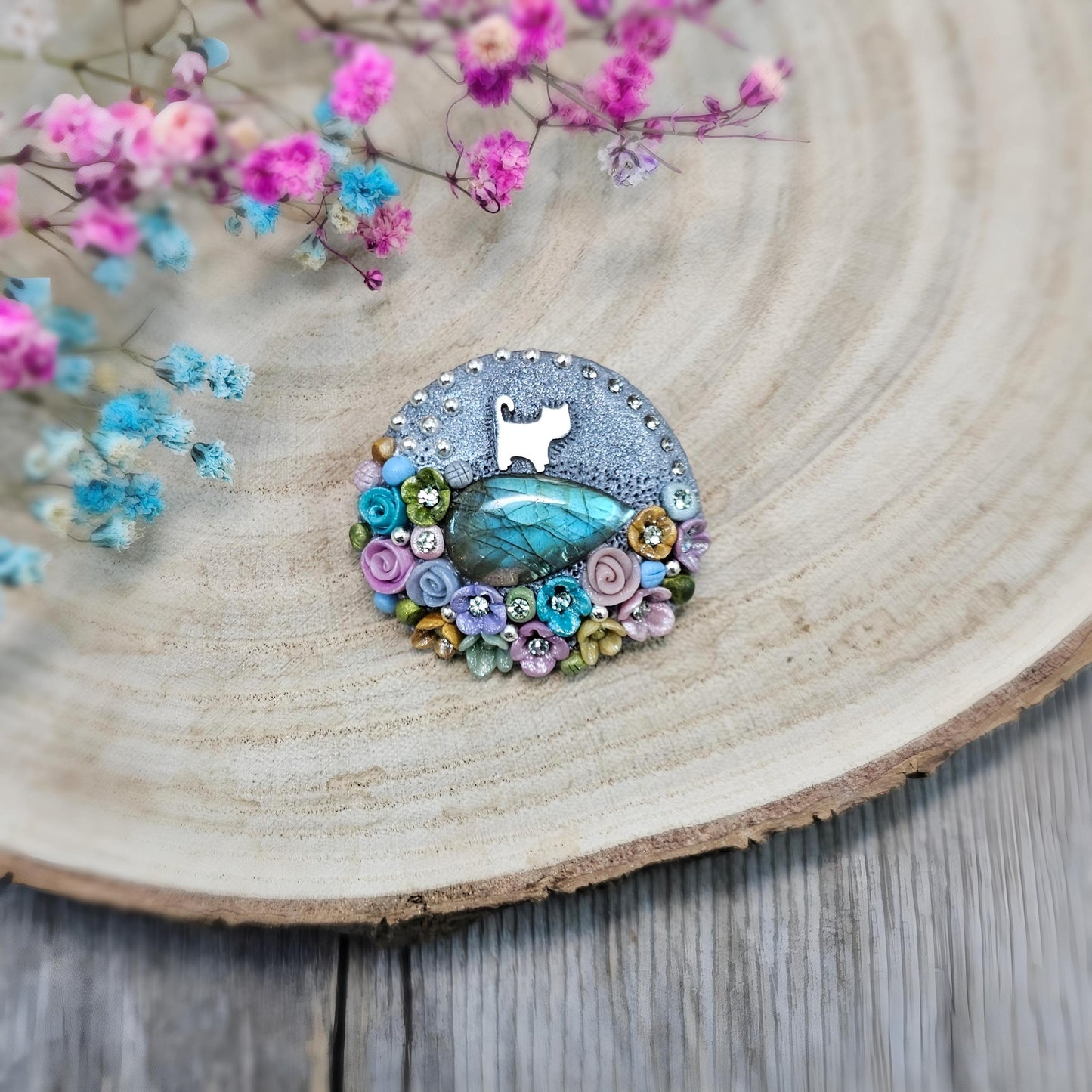 1️⃣ Front view: A handcrafted labradorite brooch featuring a silver-tone cat charm, surrounded by delicate polymer clay flowers in pastel colors. The shimmering gemstone displays a magical glow depending on the lighting.
2️⃣ Back view: The backside of the handmade cat brooch, featuring a secure screw-back pin for comfortable wear. A small red heart detail and subtle embellishments add an extra touch of uniqueness.
Let me know if you need any tweaks! 😊