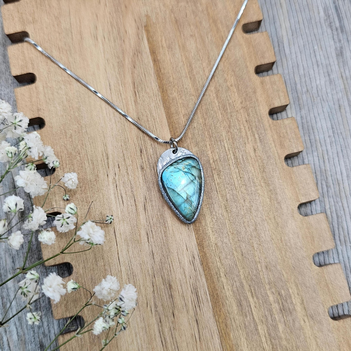Handmade labradorite pendant on a stainless steel chain, glowing in natural light. Magical blue gemstone set in polymer clay.