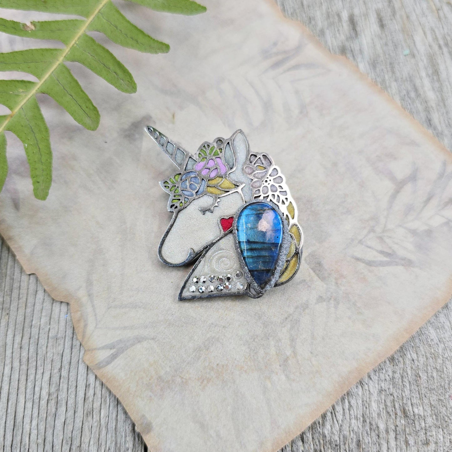 Handmade unicorn brooch featuring a shimmering labradorite, crafted from polymer clay with stainless steel backing – magical and unique fantasy jewelry.