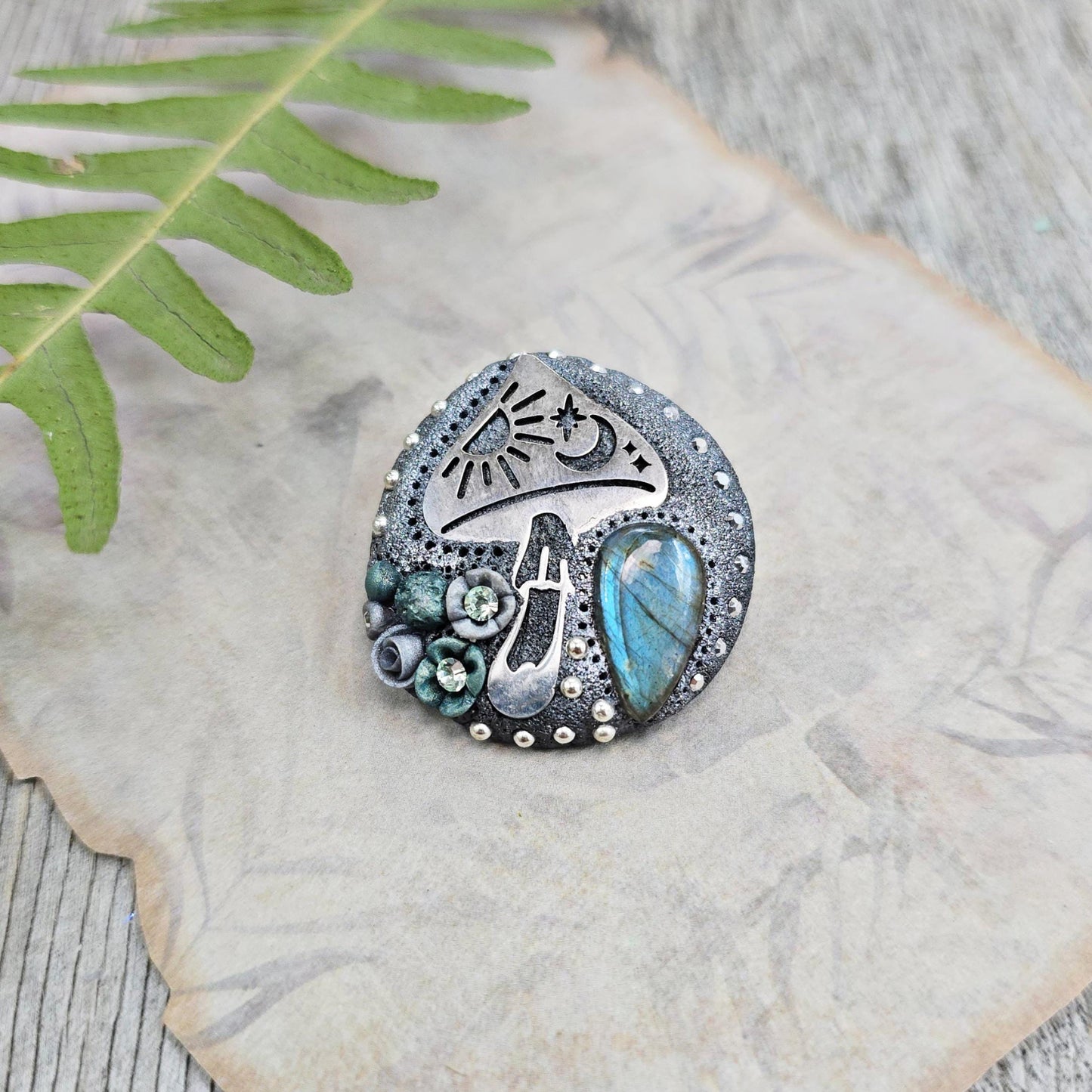 Handmade polymer clay brooch featuring a magical mushroom and a glowing labradorite stone, with stainless steel pin – forest-inspired mystical jewelry.