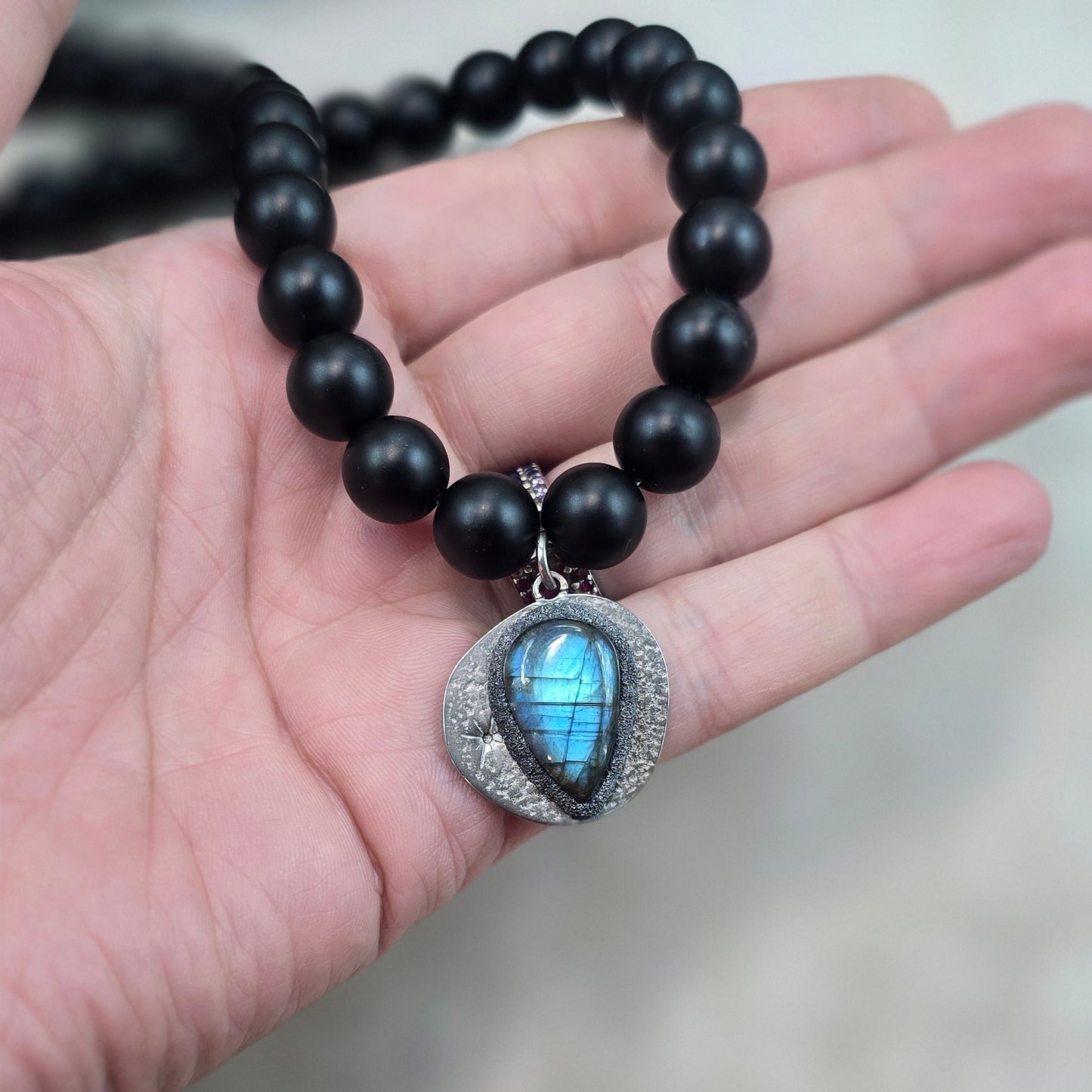 Trumpas vėrinys su labradoritu ir šungitu