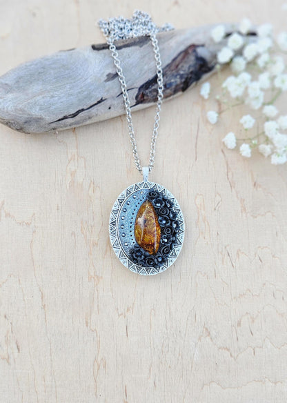 Pendant locket with amber, handmade flowers from polymer clay. On the other side, there is a locket with a heart that opens, inside which you can put a photo or a scent. A great gift for a loved one, or for yourself as a protective amulet.