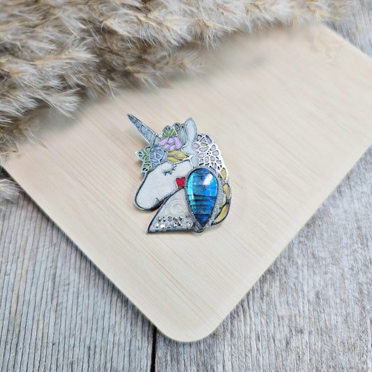 Handmade unicorn brooch featuring a shimmering labradorite, crafted from polymer clay with stainless steel backing – magical and unique fantasy jewelry.