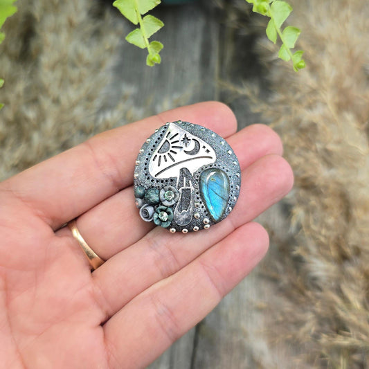 Handmade polymer clay brooch featuring a magical mushroom and a glowing labradorite stone, with stainless steel pin – forest-inspired mystical jewelry.